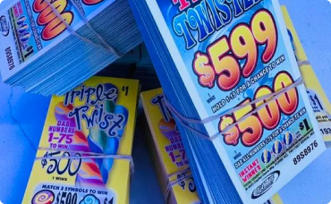 A winning lottery ticket with symbols and several $100 bills fanned out next to it.