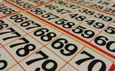 A winning lottery ticket with symbols and several $100 bills fanned out next to it in bingo.