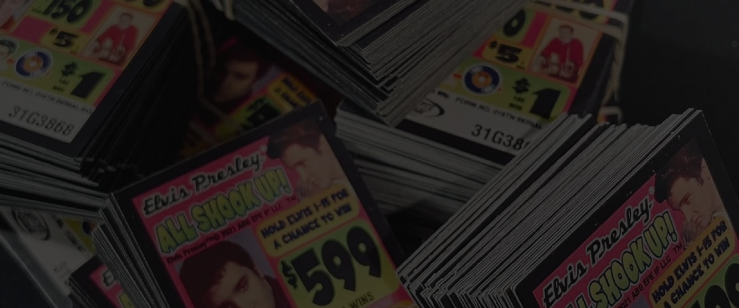 A group of people at a bingo hall, smiling with bingo cards and devices on the table.