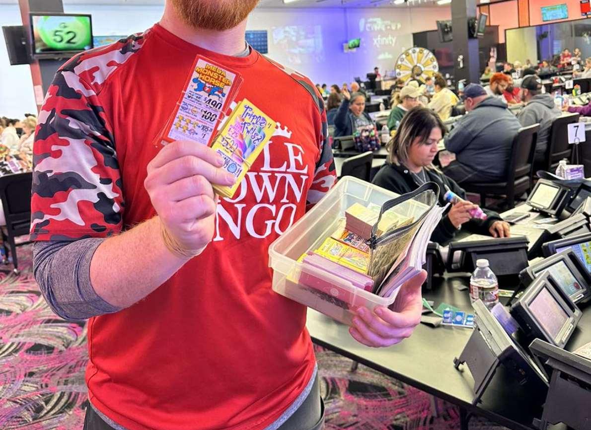 A winning lottery ticket with symbols and several $100 bills fanned out next to it..
